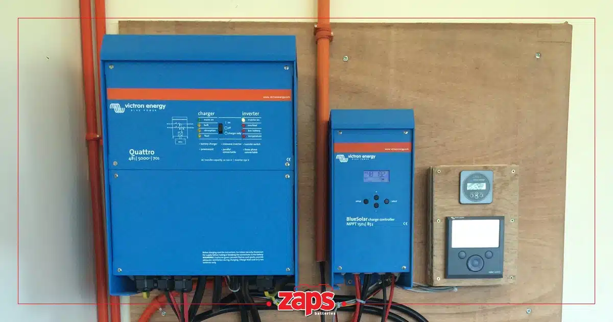 Εξοπλισμός ηλιακής ενέργειας Victron Energy με μετατροπέα, ρυθμιστή φόρτισης και οθόνες σε ξύλινη επιφάνεια.